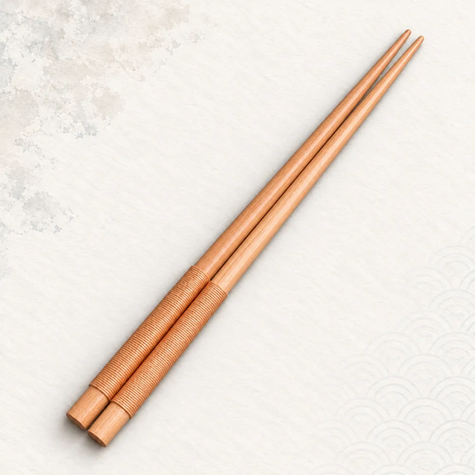 Paire de baguettes japonaises en bois clair avec cordon beige enroulé autour des manches.