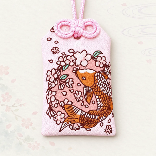 Omamori japonais rose de bonne fortune, brodé d’une carpe koï orange et de fleurs de cerisier, vue de face.