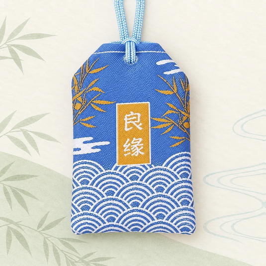 Verso de l’omamori japonais bleu, avec inscription blanche sur fond doré, bambous et vagues.