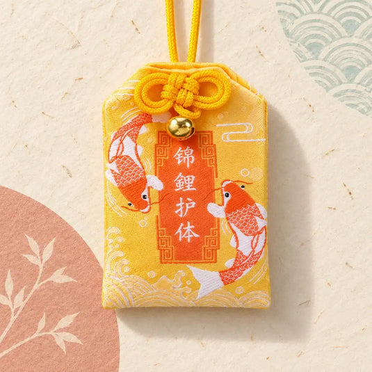 Omamori japonais jaune pour la réussite, avec deux carpes koï brodées et un grelot doré.