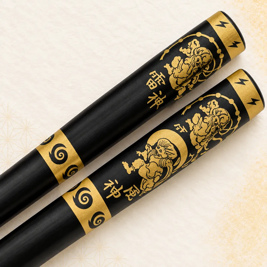 Très gros plan des personnages, inscriptions et ornements dorés sur les baguettes japonaises Oni Kuro.