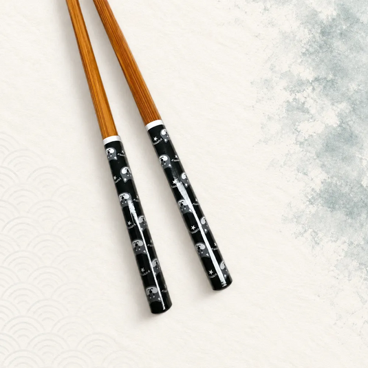 Paire de baguettes japonaises en bambou brun avec manches noirs à motifs Shiba Inu. Vue proche.