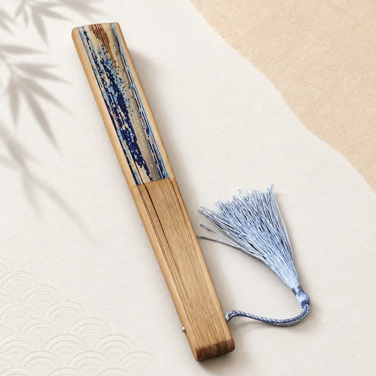 Éventail japonais Hokusai fermé, avec monture en bambou et pompon bleu clair.
