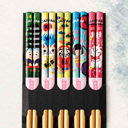 Lot de cinq paires de baguettes japonaises en bambou, avec motifs Japan colorés et support noir. Vue rapprochée.