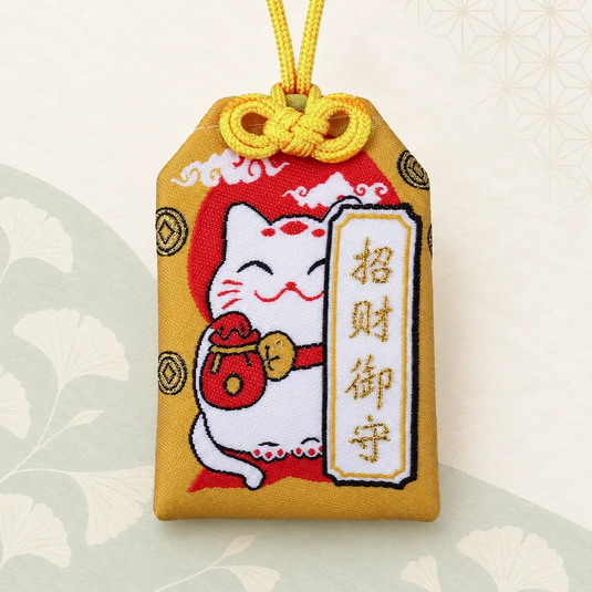 Omamori japonais doré avec Maneki-neko et inscription brodée, vue de face.