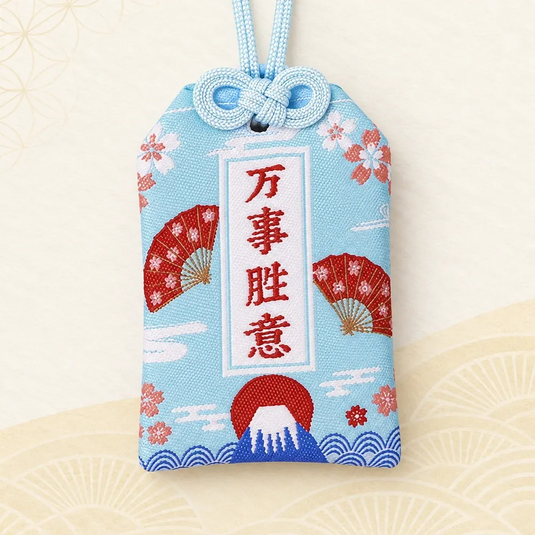 Omamori japonais bleu aqua pâle, brodé du mont Fuji, d’éventails rouges et de fleurs de cerisier.