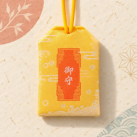 Verso de l’omamori japonais jaune pour la réussite, avec inscription blanche et double cordon jaune.