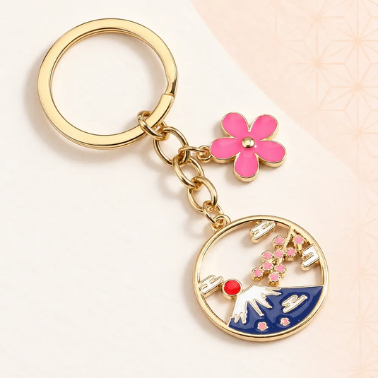 Porte-clés japonais Fujisan doré, avec médaillon ajouré du mont Fuji et fleur rose.